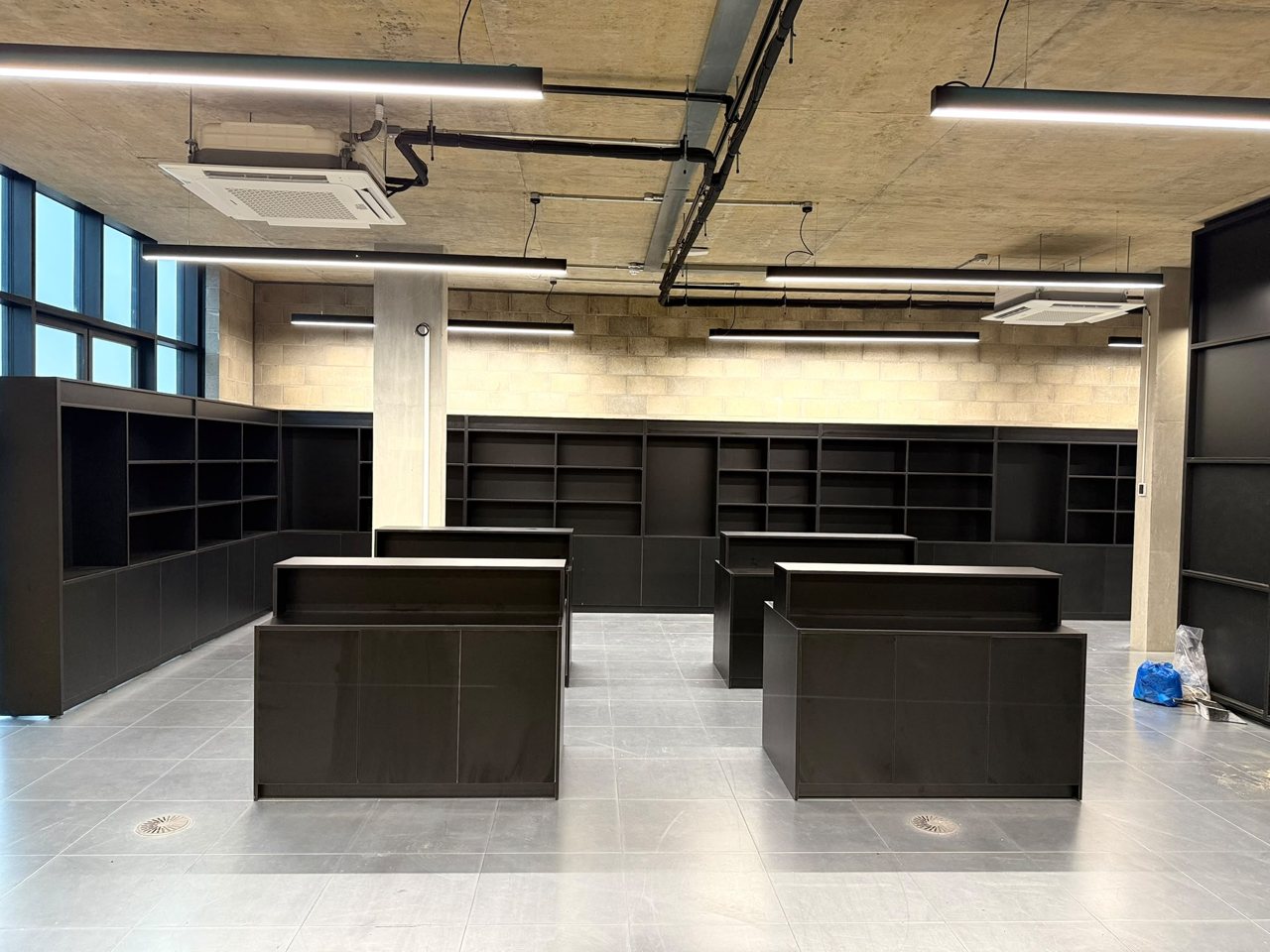 Commercial interior fitted by the MALCON team with full-height black shelving along the walls and matching display counters