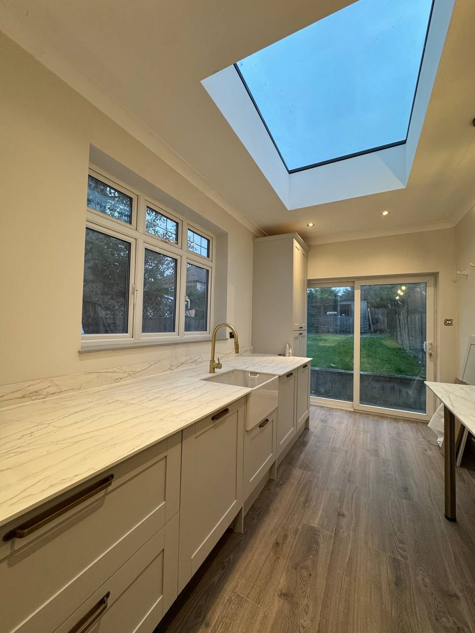 Shaker-style kitchen under a roof lantern with stone-effect worktops, renovated by MALCON