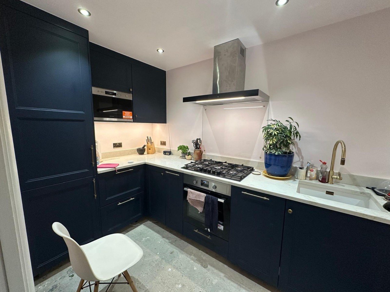 Completed MALCON navy Shaker-style kitchen in London with a light stone-effect worktop, brass tap and handles