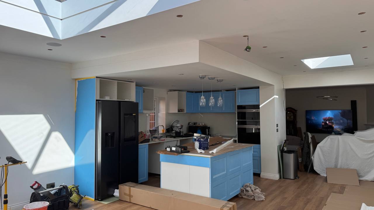 MALCON rear extension in Chelmsford: kitchen under a roof lantern with island and pendant lights, cabinetry still in protective film